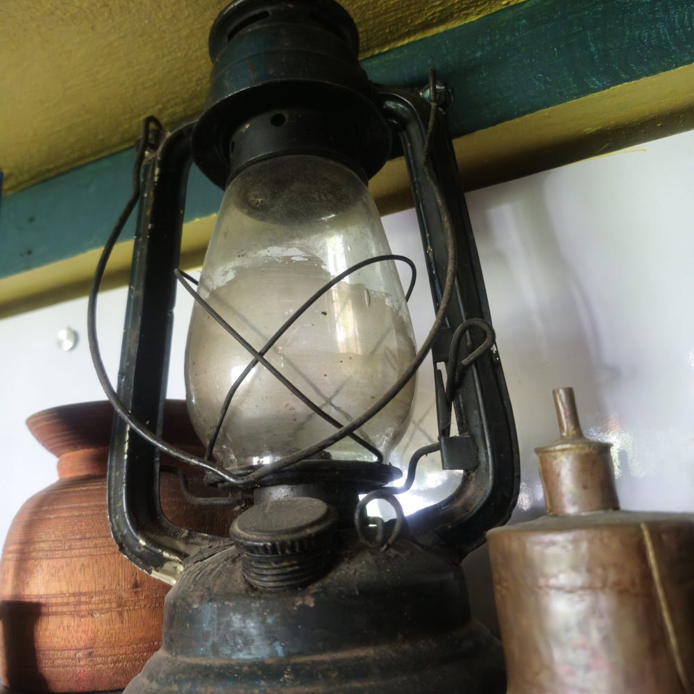 Close-up of an antique oil lantern with a glass chimney, surrounded by wooden…